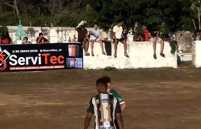 Torcedor usa coroa de flores contra sol em jogo ao lado de cemitério